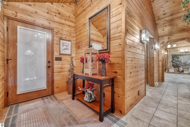 interior space with wood walls, high vaulted ceiling, and tile patterned flooring