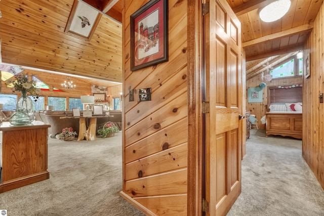 hall featuring lofted ceiling with beams, plenty of natural light, wooden walls, wood ceiling, and light carpet