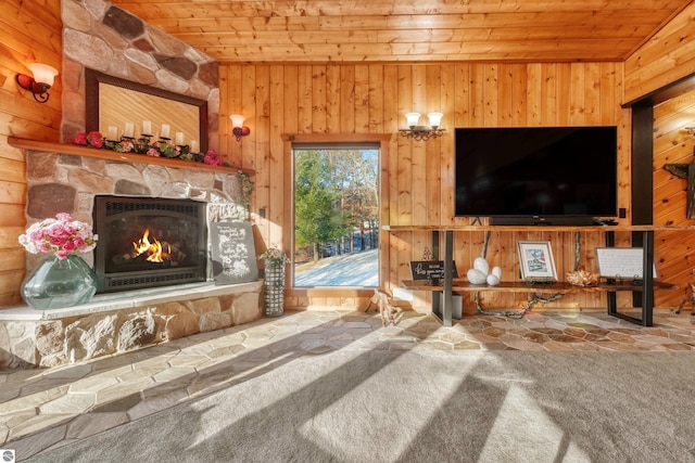 living room featuring carpet flooring, wooden walls, wooden ceiling, and a stone fireplace