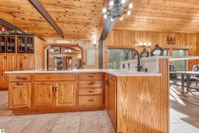 kitchen featuring sink, beamed ceiling, wooden walls, wood ceiling, and light tile patterned flooring