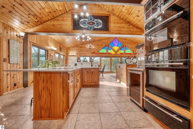 kitchen featuring wood ceiling, light tile patterned floors, double oven, and beverage cooler