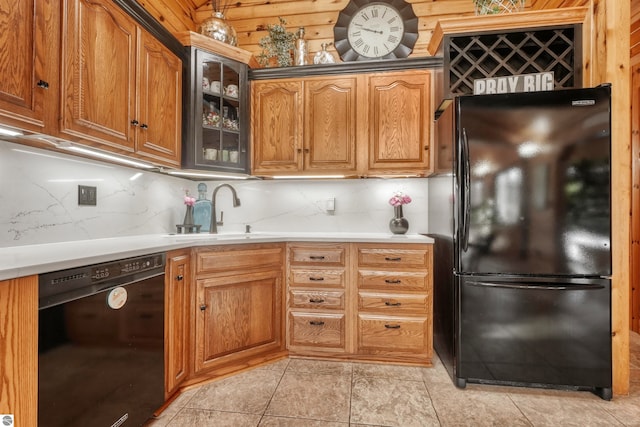 kitchen featuring decorative backsplash, wood walls, light tile patterned floors, sink, and black appliances