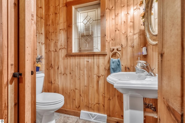 bathroom featuring tile patterned flooring, toilet, and wooden walls