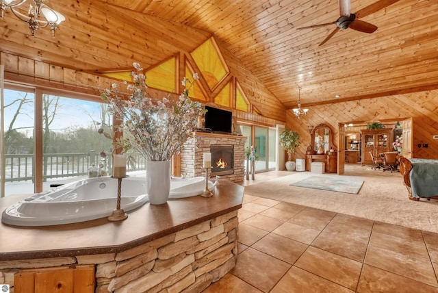 interior space featuring high vaulted ceiling, a stone fireplace, wooden walls, and a healthy amount of sunlight