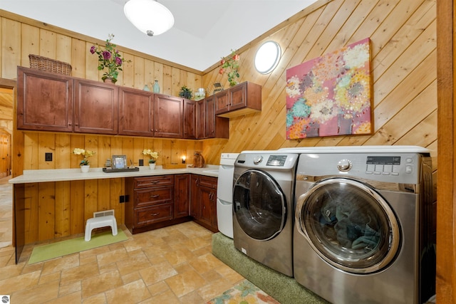 laundry area with light tile patterned flooring, independent washer and dryer, wooden walls, and cabinets