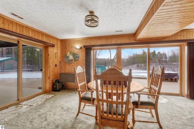 carpeted dining area with wood walls and a textured ceiling