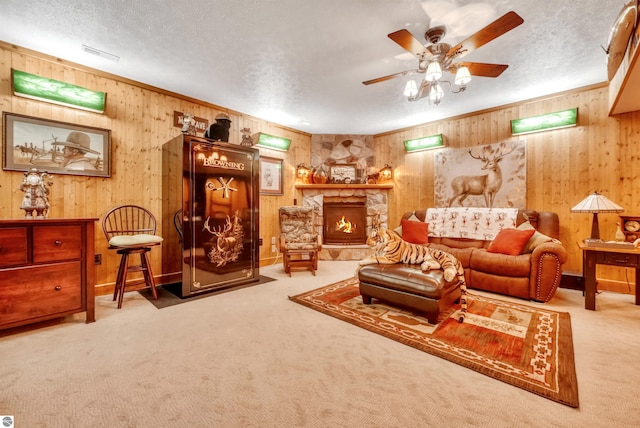 living room with carpet flooring, a textured ceiling, wooden walls, and a stone fireplace