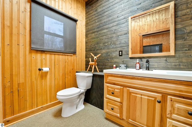 bathroom featuring wood walls, vanity, and toilet