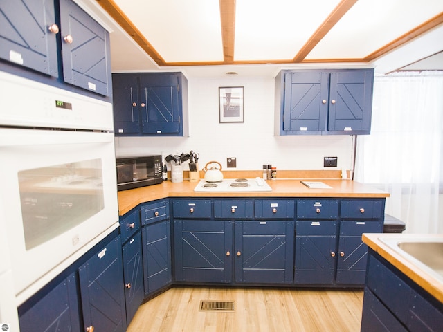 kitchen featuring white appliances, blue cabinetry, and light hardwood / wood-style floors