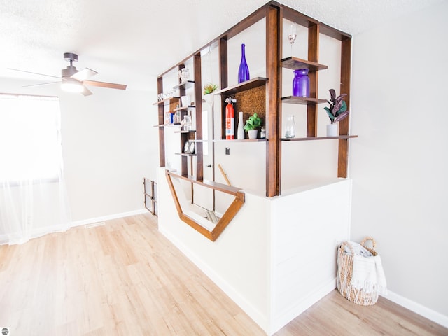 staircase featuring a textured ceiling, ceiling fan, and light wood-type flooring