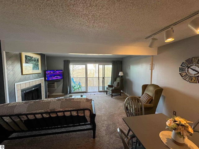 carpeted living room with a tiled fireplace, a textured ceiling, and track lighting