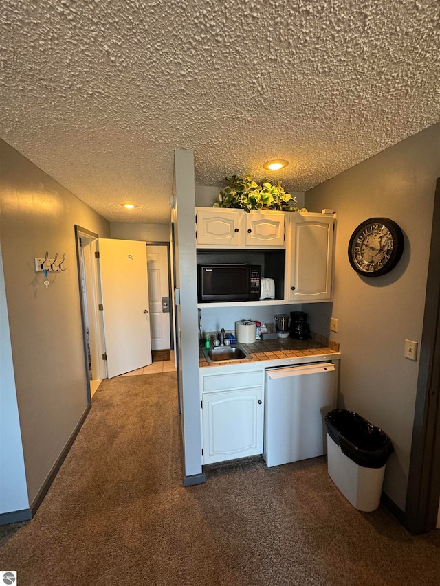 kitchen featuring white cabinets, a textured ceiling, dark carpet, dishwasher, and sink