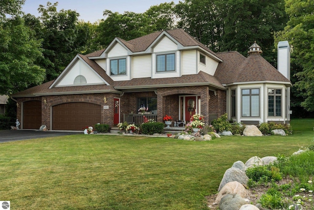 view of front of house featuring covered porch, a garage, and a front lawn