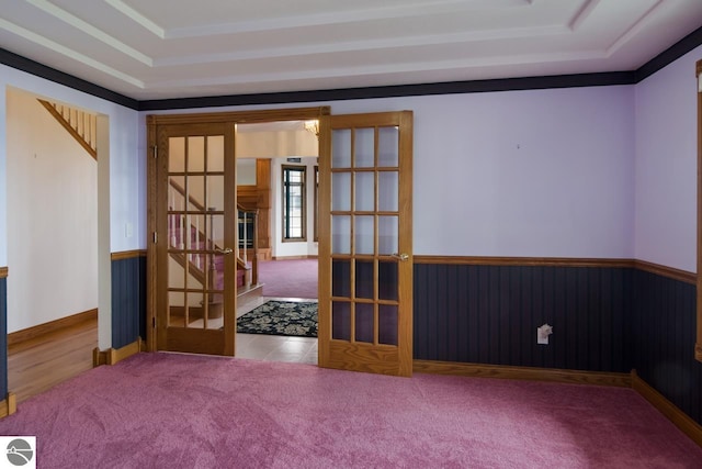 empty room featuring french doors, a raised ceiling, and light tile floors