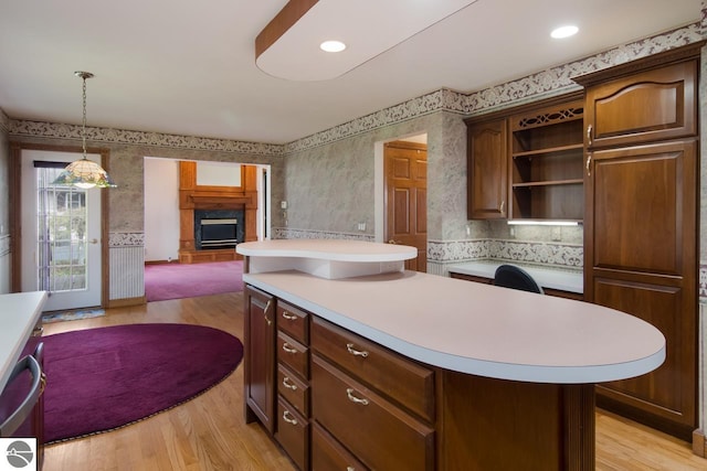 kitchen with a kitchen island, light hardwood / wood-style flooring, dark brown cabinetry, and decorative light fixtures