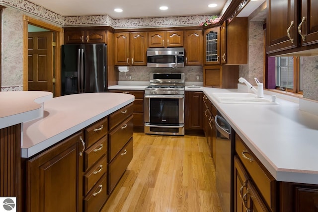 kitchen featuring sink, stainless steel appliances, light wood-type flooring, and tasteful backsplash