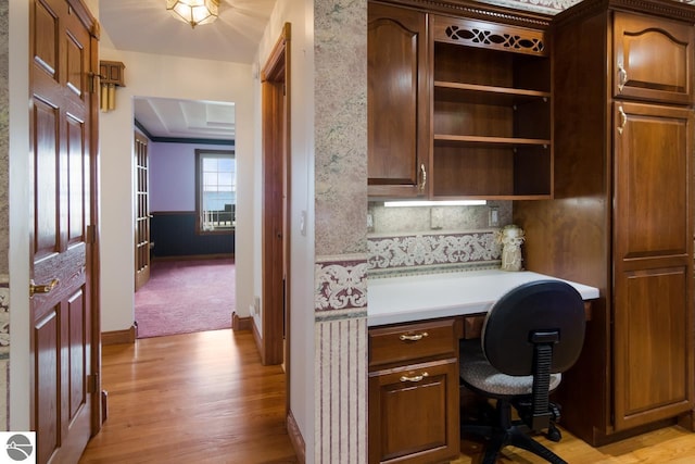 home office featuring light hardwood / wood-style flooring, built in desk, and a raised ceiling