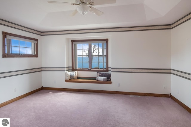 carpeted empty room featuring a raised ceiling and ceiling fan