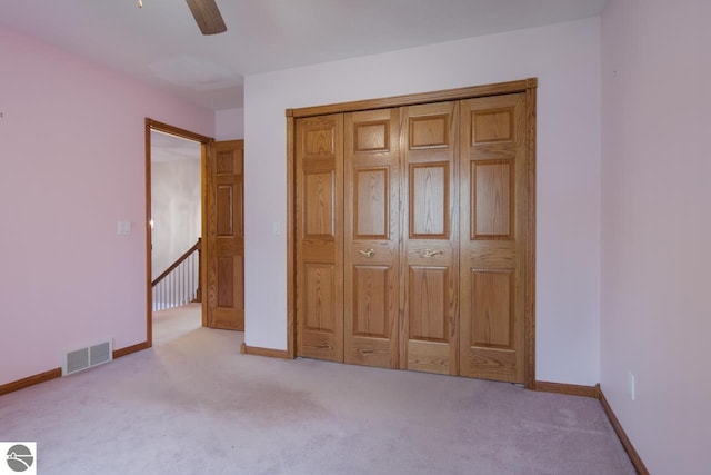 unfurnished bedroom with light colored carpet, a closet, and ceiling fan