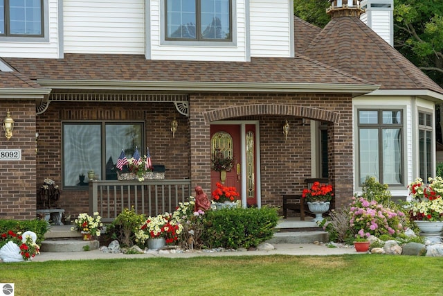 entrance to property featuring a porch and a lawn