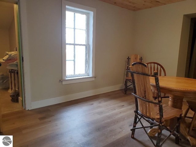 dining room featuring a healthy amount of sunlight, wood-type flooring, and wooden ceiling