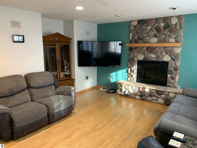 living room with a stone fireplace and light hardwood / wood-style flooring