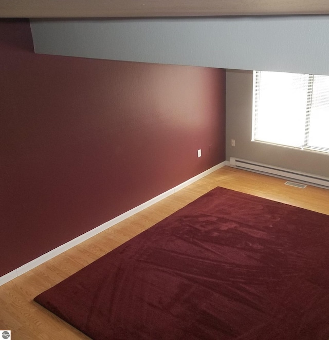 empty room with baseboard heating and light wood-type flooring