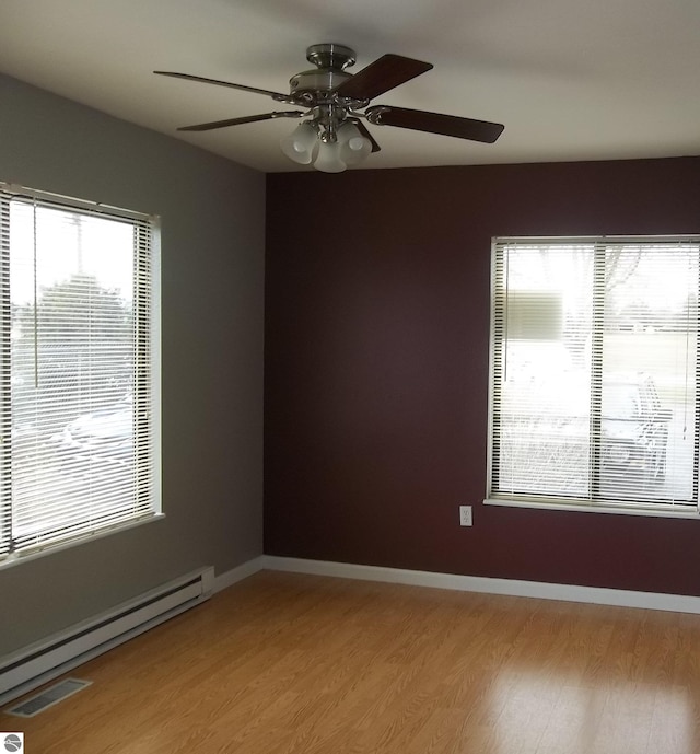 empty room featuring ceiling fan, light hardwood / wood-style floors, and a baseboard heating unit