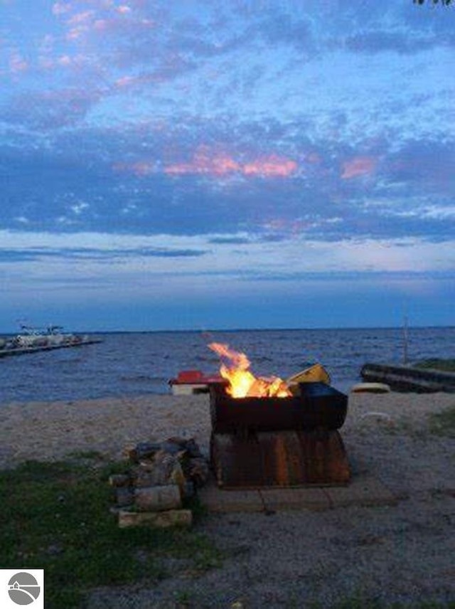 property view of water featuring a beach view and an outdoor fire pit