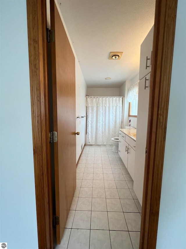 bathroom featuring a shower with shower curtain, tile patterned floors, vanity, and toilet