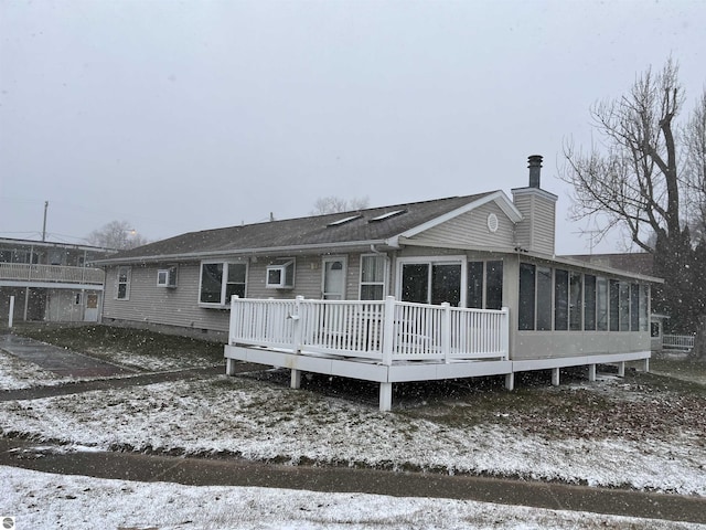 snow covered house with a sunroom and a deck