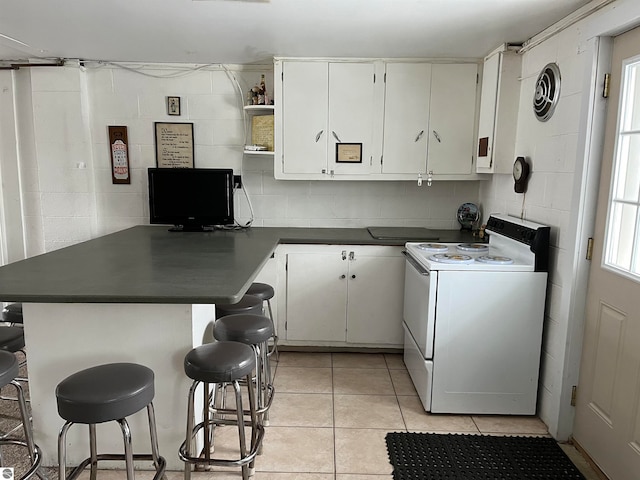 kitchen featuring a kitchen breakfast bar, electric stove, white cabinetry, and kitchen peninsula