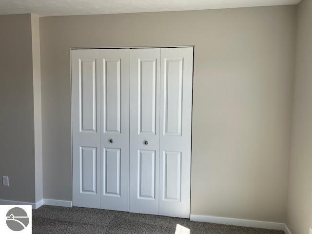 unfurnished bedroom featuring dark colored carpet and a closet