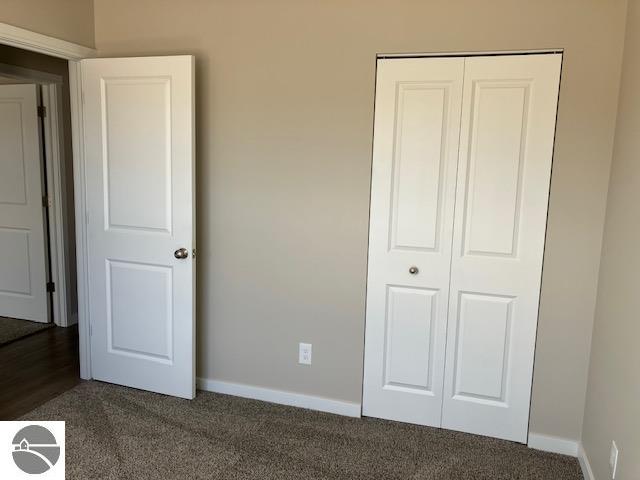 unfurnished bedroom featuring a closet and dark colored carpet