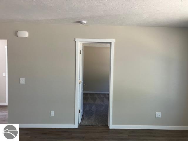 spare room with dark hardwood / wood-style flooring and a textured ceiling