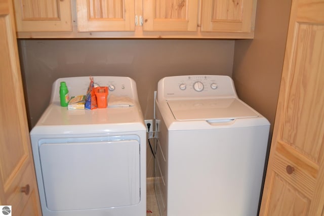 laundry area featuring cabinets, tile floors, and washer and clothes dryer