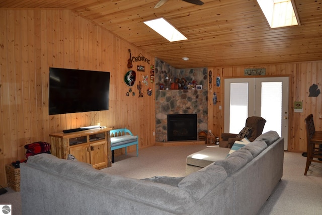 living room with wood ceiling, a fireplace, light carpet, and wooden walls