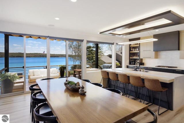 dining area with sink, a water view, and light wood-type flooring