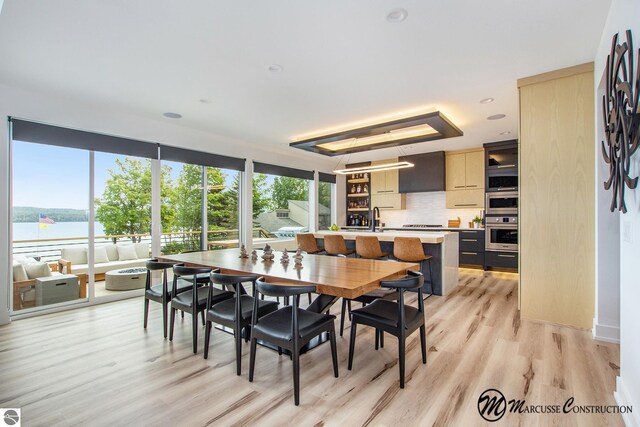 dining space featuring light hardwood / wood-style flooring, sink, and a water view