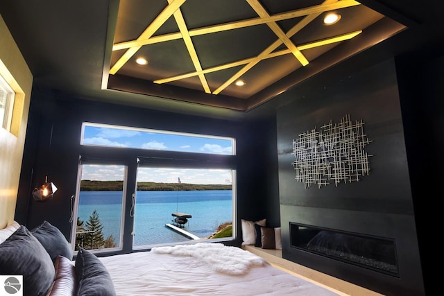 bedroom featuring a chandelier, a water view, and a tray ceiling