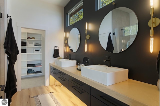 bathroom with a shower, dual bowl vanity, and built in shelves