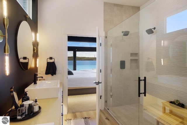 bathroom featuring a water view, a shower with door, and sink