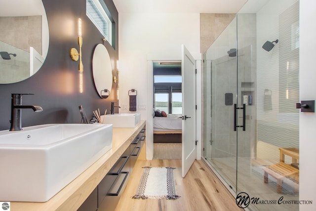 bathroom featuring hardwood / wood-style floors, double vanity, and a shower with shower door