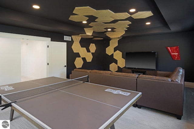 rec room with light colored carpet and a raised ceiling