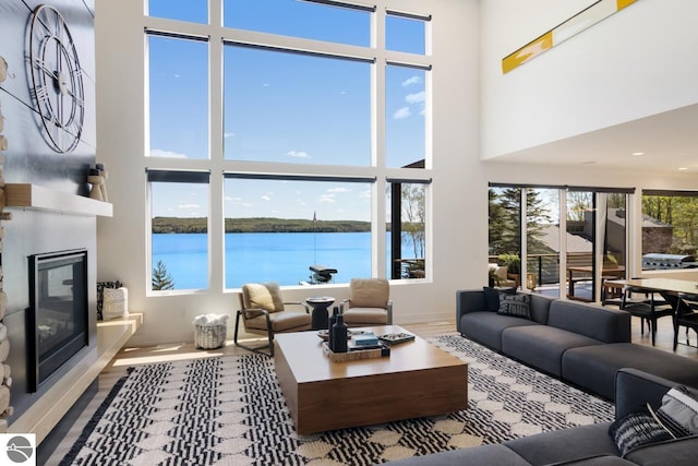 living room with a water view, hardwood / wood-style flooring, and a high ceiling