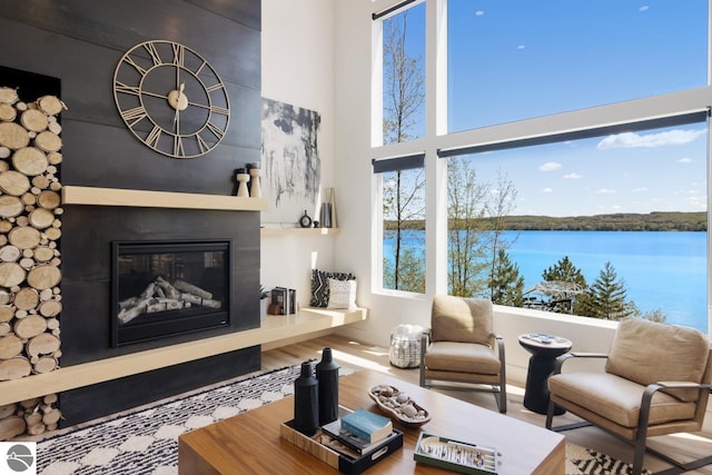 living room featuring hardwood / wood-style flooring, a towering ceiling, and a water view