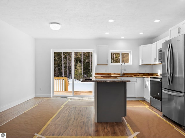 kitchen with a kitchen island, light hardwood / wood-style floors, stainless steel appliances, and white cabinets