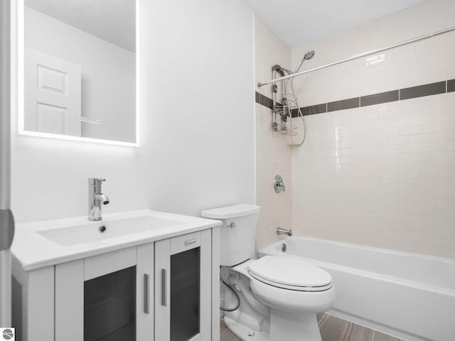 full bathroom featuring tiled shower / bath combo, vanity, and toilet