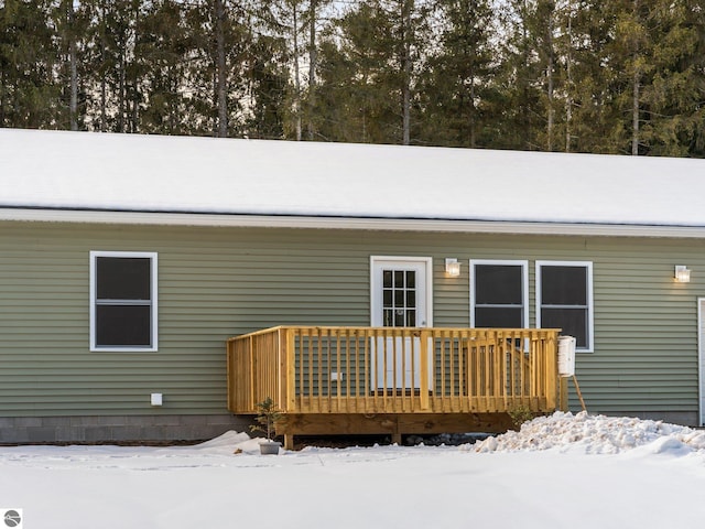 snow covered back of property featuring a wooden deck