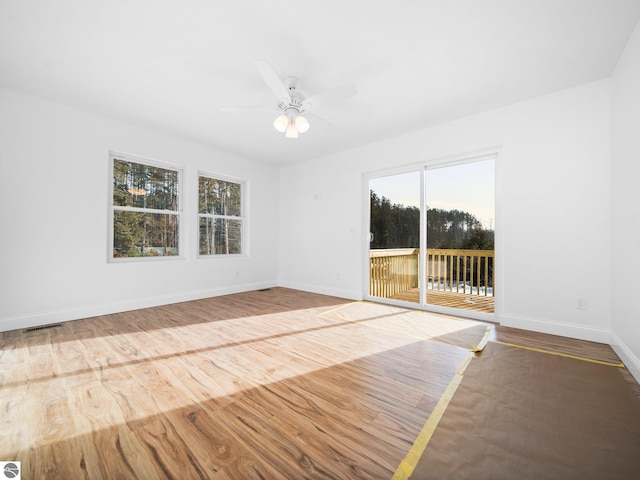 empty room featuring plenty of natural light, ceiling fan, and hardwood / wood-style floors